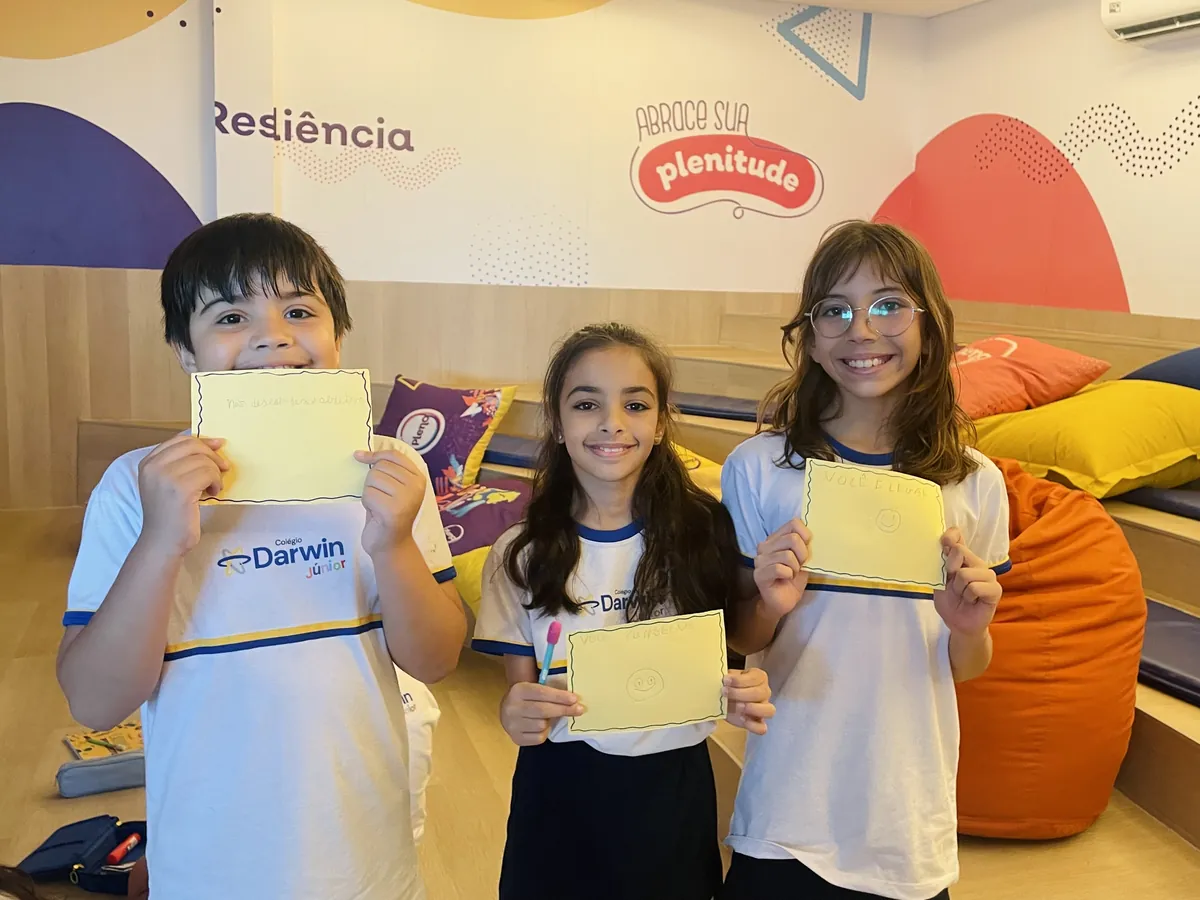 Três alunos dos Anos Finais segurando cartões amarelos em atividade de Cultura de Paz.