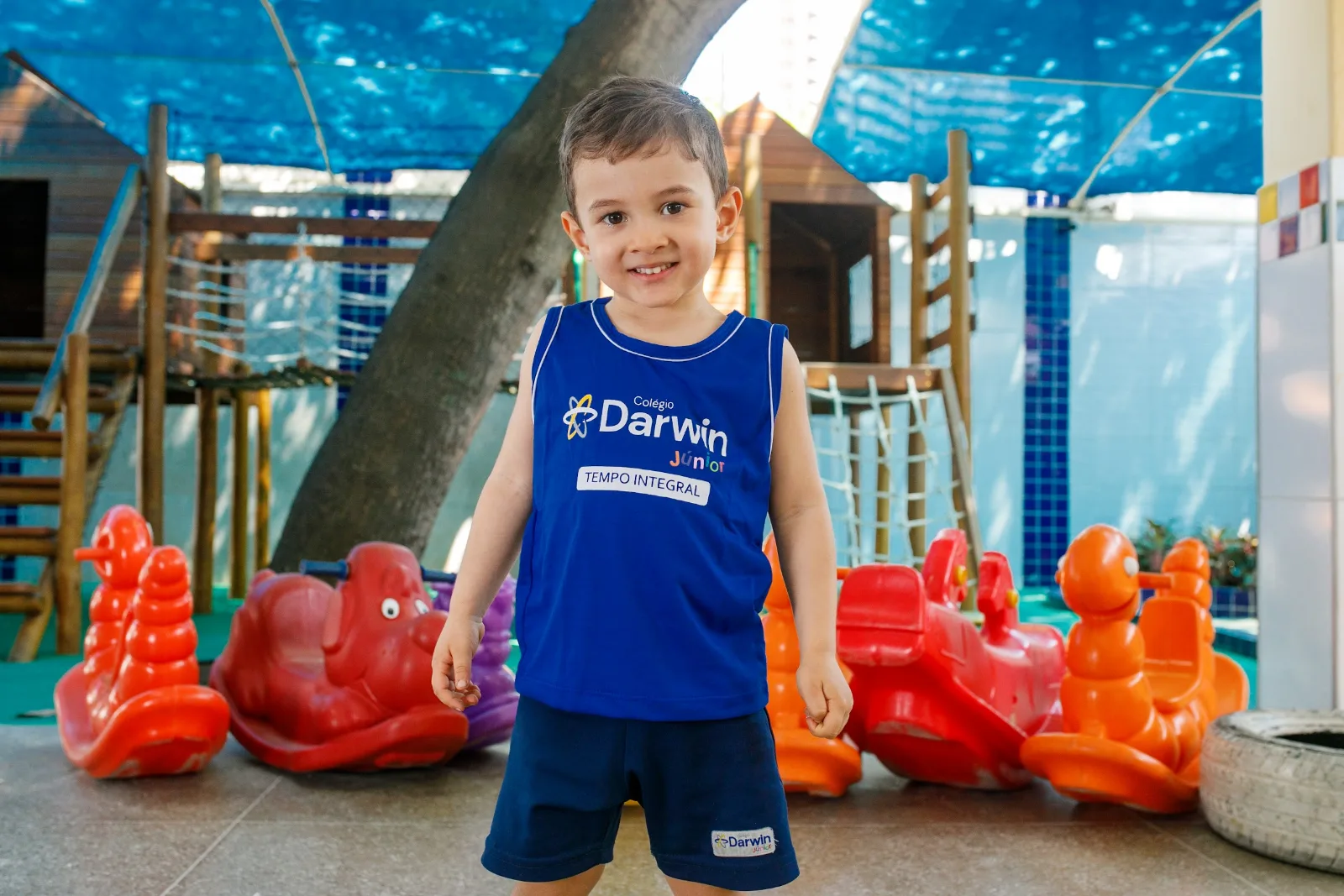 Aluno do Tempo Integral do Darwin no pátio da Sede Aldeota, diante dos brinquedos de balanço.