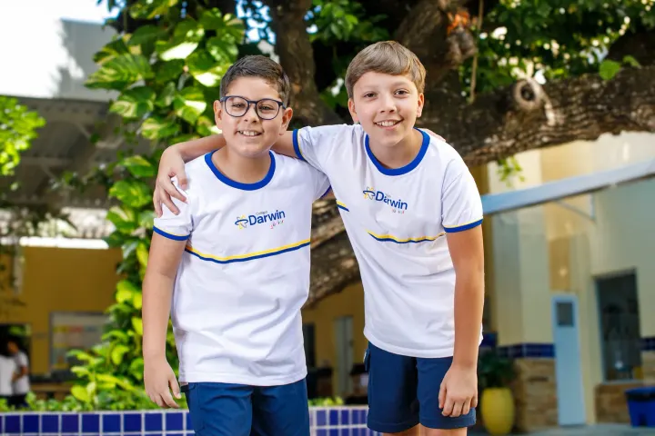 Dois alunos dos Anos Iniciais do Darwin abraçados e sorrindo no pátio