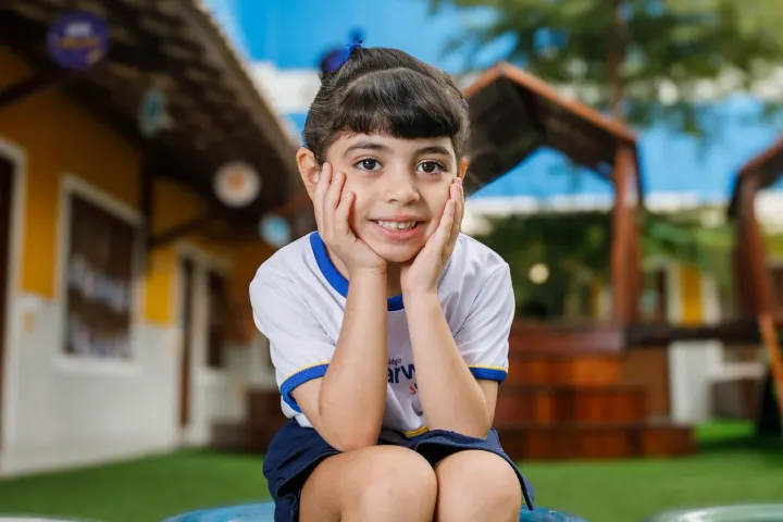 Criança da Educação Infantil do Darwin sorrindo no gramado do parquinho